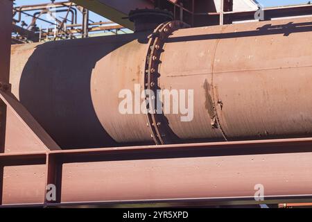 Primo piano di un grande tubo industriale arrugginito con una flangia alla luce del sole Foto Stock