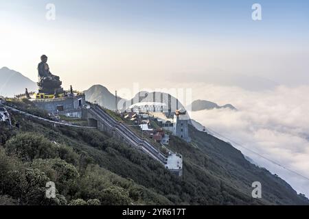 La statua del grande Buddha sulla cima di Fansipan in Vietnam, con la stazione di montagna della funivia alle spalle Foto Stock