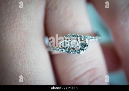 Primo piano di un anello diamantato sul dito con dettagli intricati Foto Stock