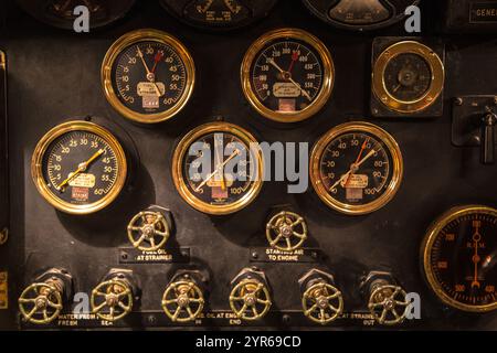 Una raccolta di quadranti e indicatori di vecchio stile, tutti dorati e neri, sono visualizzati su uno sfondo nero. Gli indicatori sono disposti in fila, con un po' di o Foto Stock