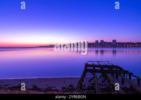 Lo skyline di Porto si riflette sul fiume douro al tramonto con un vecchio molo in primo piano, creando un'atmosfera romantica e tranquilla a porto, portogallo Foto Stock