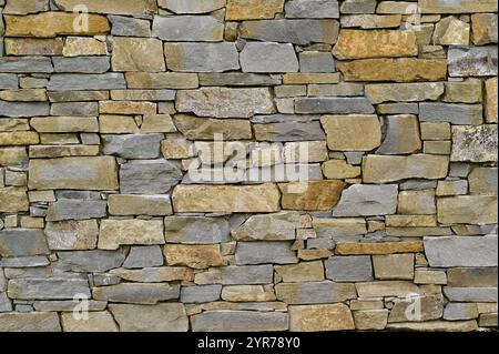 un muro di pietra fatto di mattoni di forme e dimensioni diverse Foto Stock