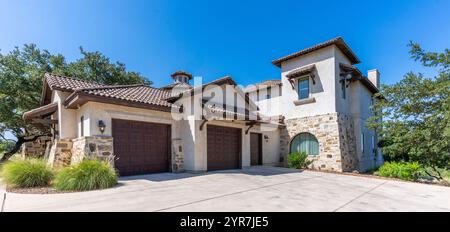 Bella casa moderna con accenti in pietra e grande vialetto in un ambiente soleggiato Foto Stock