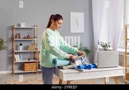 Una bella donna mette un tappetino per il fitness nella sua borsa, primo piano Foto Stock
