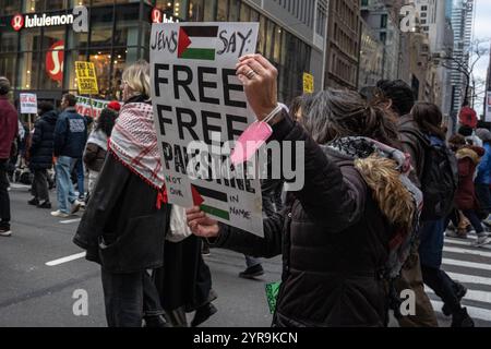 Una donna ha un segno con parole che dicono "gli ebrei dicono Palestina libera” mentre marciava con i manifestanti pro-palestinesi per la "giornata internazionale della solidarietà per il popolo palestinese” a New York. Centinaia di manifestanti pro-palestinesi si radunano al Columbus Circle per la "giornata internazionale della solidarietà per il popolo palestinese” a New York. (Foto di Derek French / SOPA Images / Sipa USA) Foto Stock