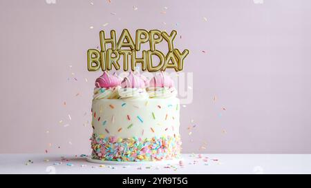 Torta di compleanno rosa con striscione oro per buon compleanno e spruzzette colorate Foto Stock