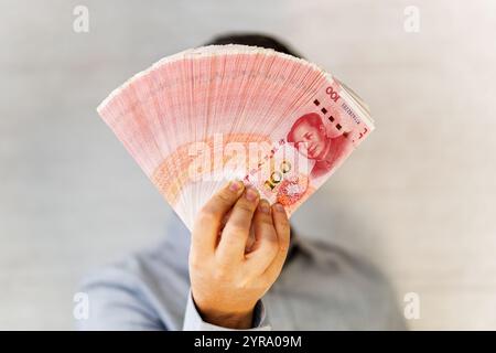 Yuan cinese nelle mani. Uomo d'affari in camicia blu con un Chineseyuan. un fan dei soldi Foto Stock