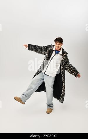 Un uomo vestito con stile con un cappotto oversize si posa giocosamente sotto le luci da studio. Foto Stock