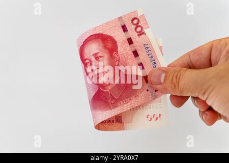 Uomo d'affari che detiene la banconota dello Yuan cinese per il pagamento su sfondo bianco. La banconota Yuan è la valuta di scambio principale e popolare nel mondo. Investigatori Foto Stock