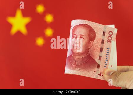Banconota cinese da 100 yuan con la bandiera cinese sullo sfondo Foto Stock