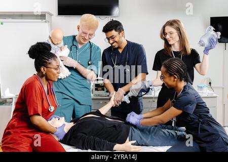 Un gruppo eterogeneo di professionisti del settore medico, tra cui medici e infermieri, in piedi insieme e sorridenti per una foto di gruppo in un ambiente ospedaliero. Foto Stock