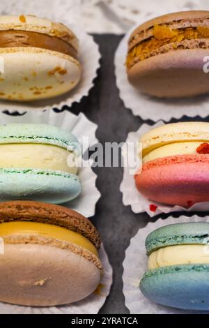 Un vivace assortimento di macaron colorati esposti su un piatto di ardesia. Perfetto per dessert, pasticceria francese e prelibatezze gourmet. Foto Stock