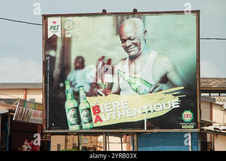 Billboard Advertising Local Beer in Togo con un uomo sorridente che versa un bicchiere Foto Stock