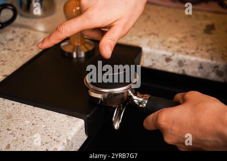 Il barista sta sta tenendo in mano un portafiltro con caffè macinato. Foto Stock