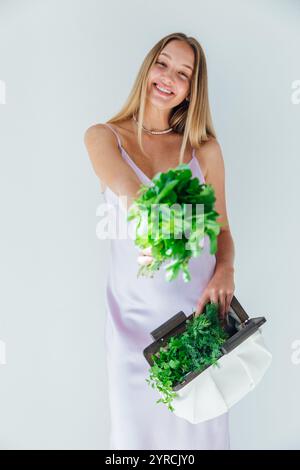 Bella donna bionda con un sacchetto di verdure verdi per una dieta Foto Stock