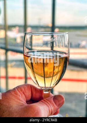 Bicchiere di vino di rosa davanti a una finestra nella business lounge di un aeroporto Foto Stock