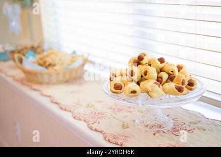 Mini Hot Dogs avvolti nella pasticceria su un piatto di portata in vetro vicino alla finestra Foto Stock