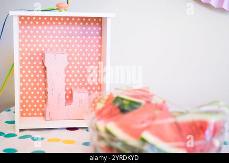 Decorazioni a pois rosa con fette di anguria e lettera L in legno - vibrazioni estive per feste Foto Stock