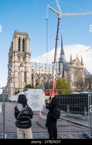 I visitatori leggono i cartelli sulla riapertura della cattedrale di Notre Dame, Parigi, dopo l'incendio del 15 aprile 2019. La riapertura al pubblico è prevista per il 7-8 dicembre 2024. Foto Stock