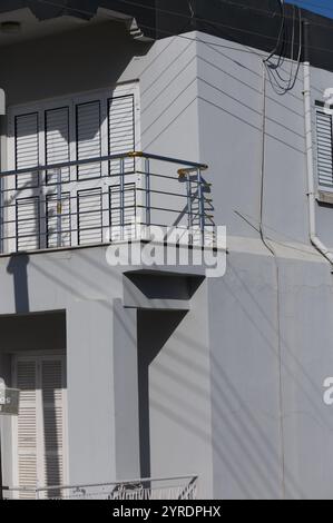 La luce del sole mette in risalto il design unico di un balcone dell'edificio, rivelando le sue caratteristiche architettoniche affascinanti. Foto Stock