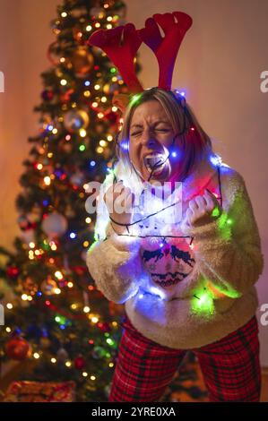 Una donna con un costume natalizio avvolto da luci colorate urla Foto Stock