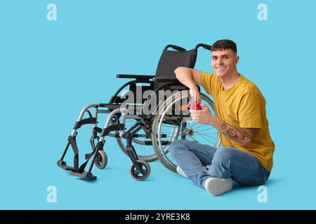 Bel giovane uomo felice con pinze che riparano sedia a rotelle su sfondo blu Foto Stock