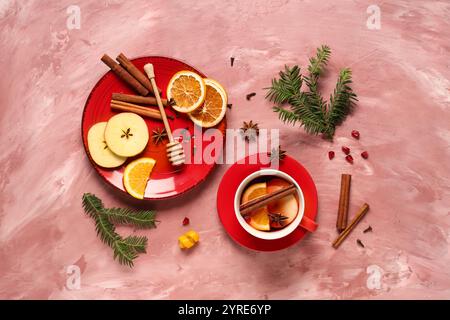 Composizione con tazza di gustoso VIN brulé e ingredienti su fondo grunge rosa Foto Stock