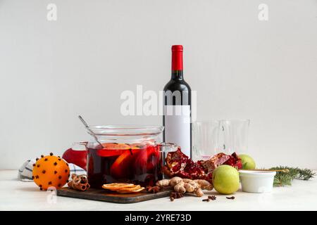 Pentola di cottura in vetro con VIN brulé caldo e diversi ingredienti su sfondo bianco Foto Stock