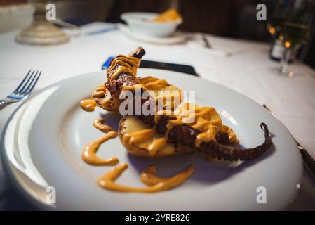 Piatto gourmet di polpo alla griglia con patate e vino bianco Foto Stock