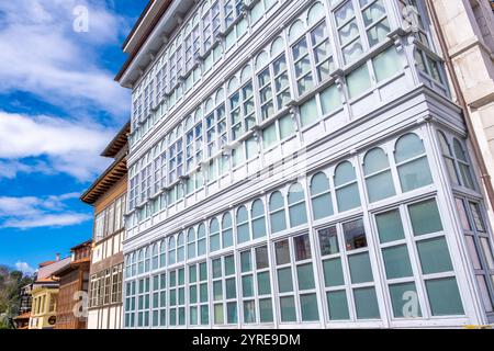 Un grande edificio bianco con numerose finestre sul lato, tipico delle case asturiane a Llanes, Asturie, nel nord della Spagna. L'edificio si erge alto e. Foto Stock