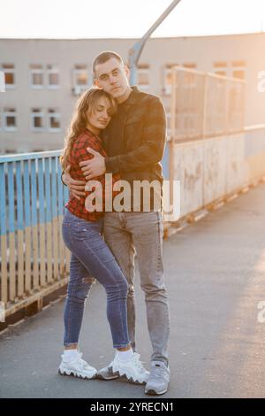 Coppia romantica che abbraccia il tramonto su un ponte. Foto Stock