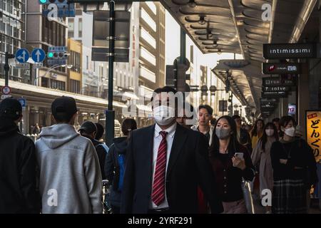 Un uomo d'affari in costume cammina per le strade di Kyoto, in Giappone, mescolando tradizione e vita moderna. Foto Stock