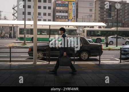 Un uomo d'affari in costume cammina per le strade di Kyoto, in Giappone, mescolando tradizione e vita moderna. Foto Stock