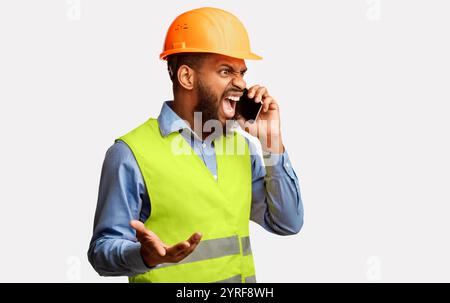 Arrabbiato Builder urlando in Cellphone Standing in Studio, Panorama Foto Stock