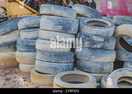 Un grande mucchio di pneumatici usati impilati uno sopra l'altro. Gli pneumatici sono soggetti agli agenti atmosferici e mostrano segni di usura. Foto Stock