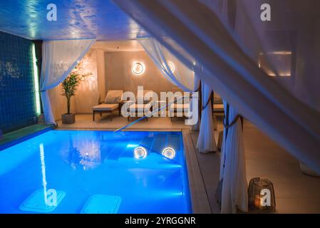 Lussuosa area piscina coperta con eleganti tendaggi nell'hotel di Marrakech Foto Stock