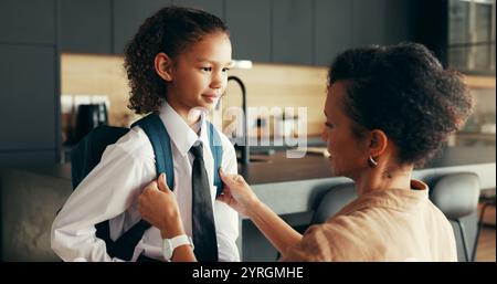 Mamma, ragazza e sorridi con lo zaino in casa per prepararsi o prepararsi per l'istruzione elementare. Appartamento, persone e genitore con bambino in uniforme per prima Foto Stock