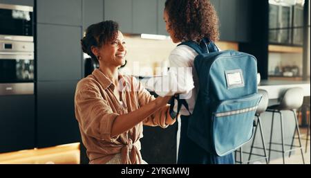 Mamma, ragazza e felice con l'uniforme scolastica in casa per prepararsi o prepararsi per l'istruzione elementare. Appartamento, persone e genitori con bambino per il primo giorno Foto Stock