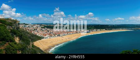 Vista panoramica mozzafiato della spiaggia di nazare con sabbia dorata, acque turchesi e affascinante paesaggio urbano tra scogliere e oceano. Portogallo Foto Stock