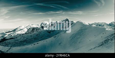 Vista panoramica delle cime innevate che si innalzano sopra una valle a zakopane, polonia, creando un paesaggio invernale mozzafiato sotto un cielo turchese Foto Stock