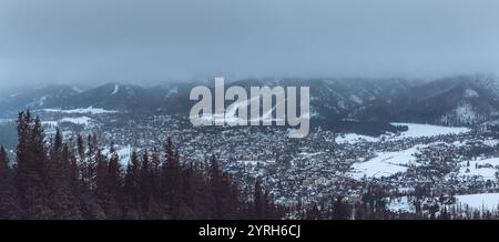 Vista panoramica del paesaggio urbano di zakopane dal monte gubalowka, dietro la pineta innevata, con piste da sci e montagne tatra innevate in inverno Foto Stock