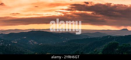 Splendida vista panoramica di barcellona e delle montagne al tramonto, con calde sfumature arancioni e rosse nel cielo Foto Stock