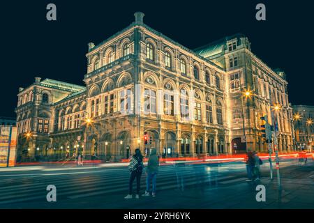 L'opera di stato di Vienna o la wiener staatsoper illuminano di notte con sentieri leggeri che passano per le auto e i turisti in attesa di attraversare la strada di vienna Foto Stock