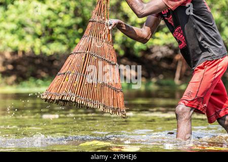 Pescatore che cattura pesce con un cesto nel fiume. Kalabo, Zambia, Africa Foto Stock