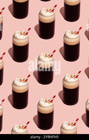 Un motivo senza cuciture di tazze di caffè spumante condite con panna e paglia a righe rosse su un morbido sfondo rosa Un design vivace e moderno per la colazione Foto Stock