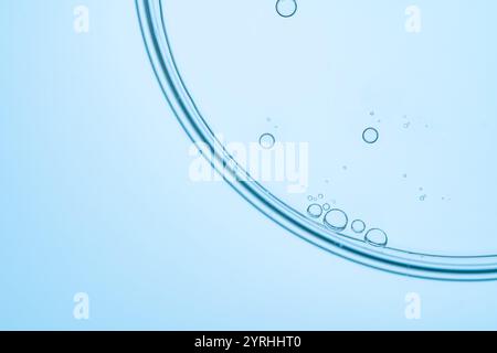 Un'immagine minimalista che mostra piccole bolle sulla superficie di un liquido trasparente azzurro. La semplicità e la chiarezza delle bolle creano una fuliggine Foto Stock