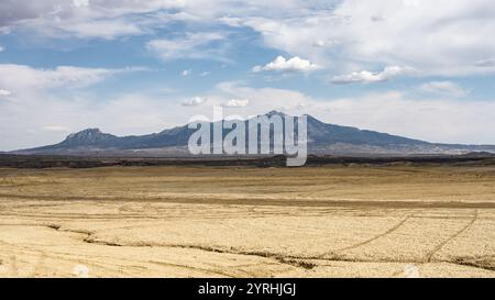 Vista mozzafiato di un vasto paesaggio desertico, caratterizzato da una prominente catena montuosa in lontananza sotto un cielo parzialmente nuvoloso catturato a Hanksville, U Foto Stock