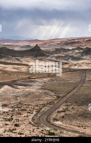 Una tortuosa strada sterrata si estende attraverso il vasto paesaggio desertico vicino a Hanskville, Utah, formazioni rocciose uniche e toni tenui creano un'atmosfera suggestiva Foto Stock