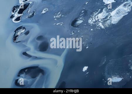 Una splendida vista aerea della costa meridionale dell'Islanda, che mostra motivi astratti di formazioni ghiacciate e acqua scura, Un'accattivante miscela di texture e col Foto Stock