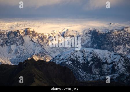 Spettacolari montagne innevate in Islanda durante l'inverno, illuminate dalla luce dolce del cielo, il terreno accidentato mostra la splendida b naturale Foto Stock